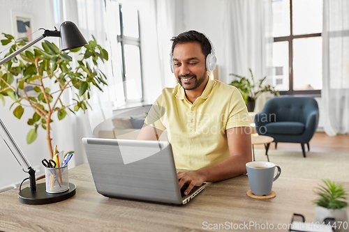 Image of man in headphones with laptop working at home