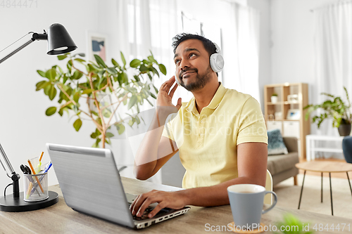 Image of man in headphones with laptop working at home