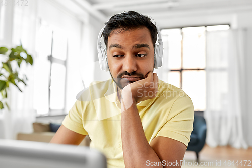 Image of man in headphones with laptop working at home