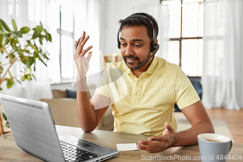 Image of indian man with headset and laptop working at home