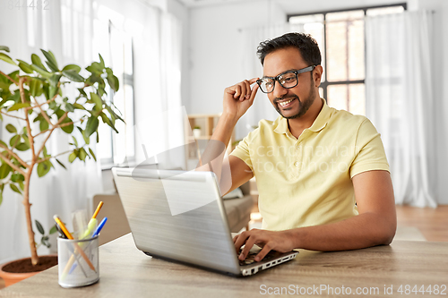 Image of indian man with laptop working at home office