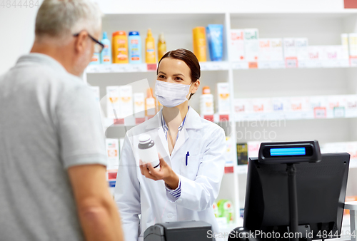 Image of apothecary in mask and senior customer at pharmacy