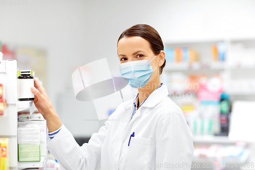 Image of female apothecary in mask with drug at pharmacy