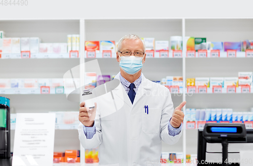 Image of senior apothecary in mask with drug at pharmacy