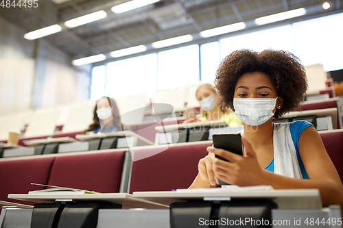 Image of student girl in mask with smartphone at lecture