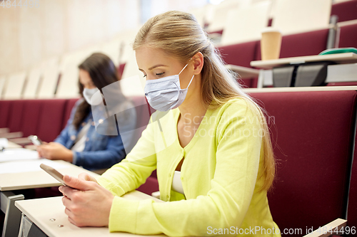 Image of student girls in masks with smartphones on lecture