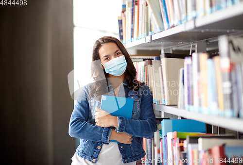 Image of student girl in mask with book at library