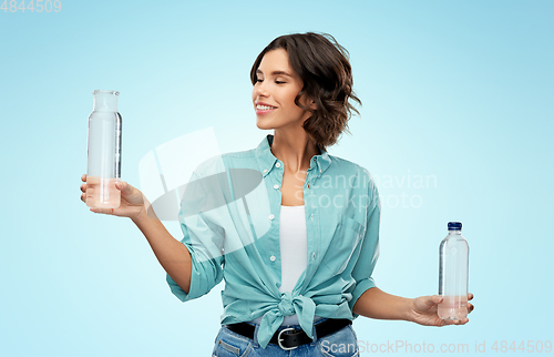 Image of smiling young woman comparing bottles of water