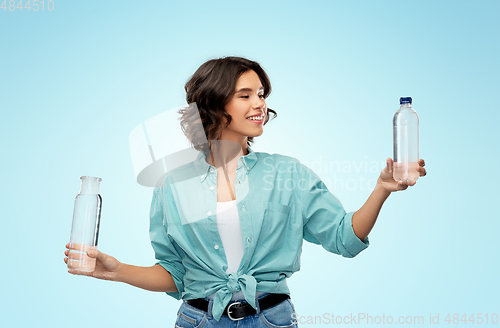 Image of smiling young woman comparing bottles of water