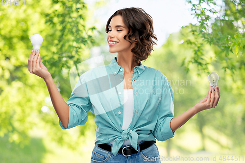 Image of smiling woman comparing different light bulbs