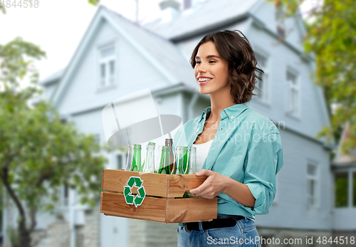 Image of smiling young woman sorting glass waste outdoors