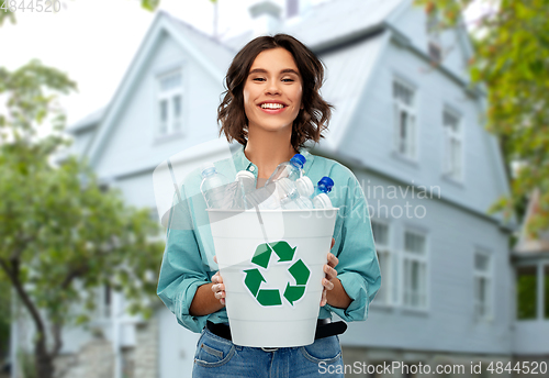 Image of smiling young woman sorting plastic waste outdoors