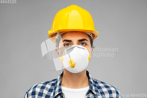 Image of female worker or builder in helmet and respirator