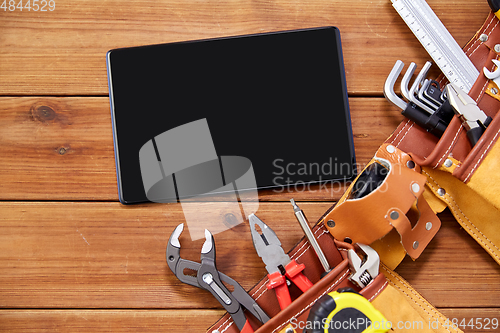 Image of tablet computer and tool belt on wooden boards