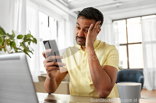 Image of indian man with smartphone at home office