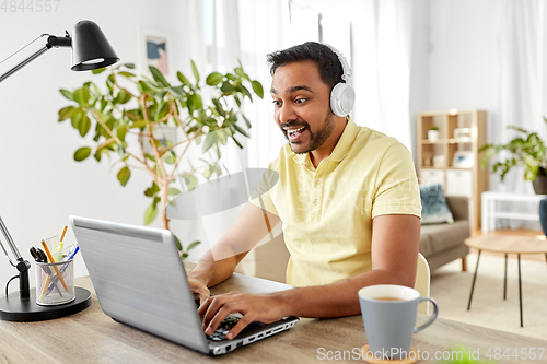 Image of man in headphones with laptop working at home