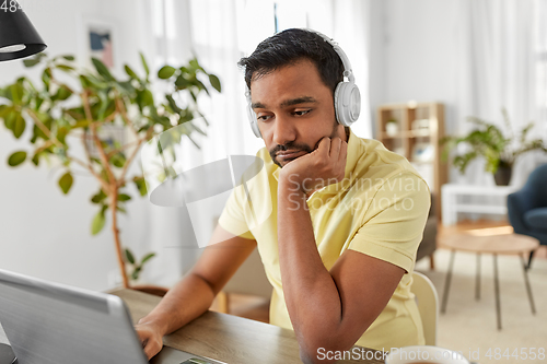 Image of man in headphones with laptop working at home