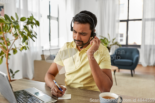 Image of indian man with headset and laptop working at home