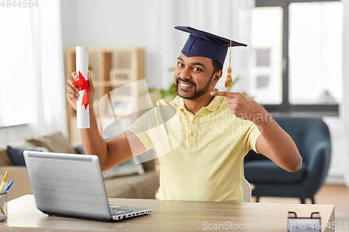 Image of indian student with laptop and diploma at home