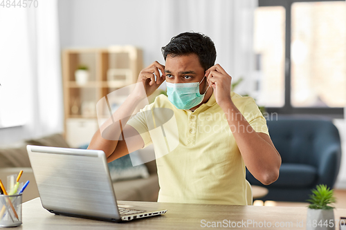 Image of indian man in mask with laptop at home office