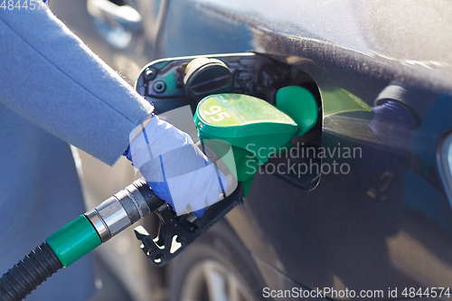 Image of close up of hand in glove filling car with petrol