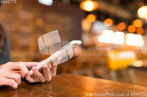 Image of Woman sending sms on cellphone in coffee shop