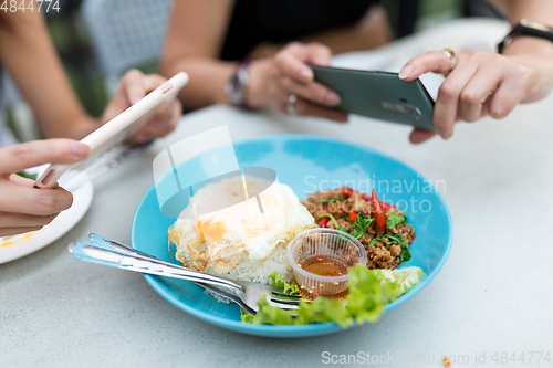 Image of Friends taking photo on thai food dishes before eating