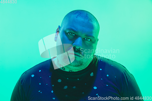 Image of Portrait of a guy with colorful neon light on green background