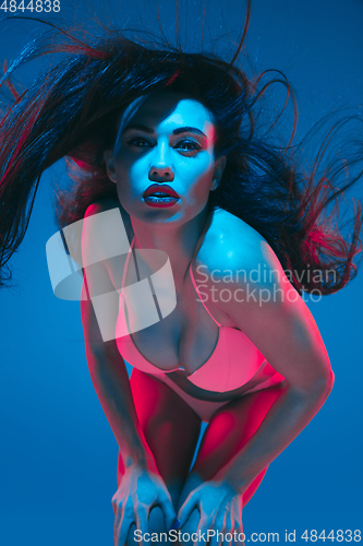 Image of Attractive brunette model on blue studio background in neon light