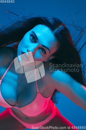 Image of Attractive brunette model on blue studio background in neon light