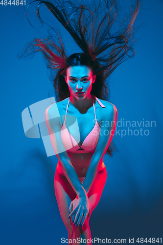 Image of Attractive brunette model on blue studio background in neon light
