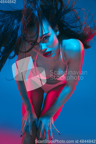 Image of Attractive brunette model on blue studio background in neon light