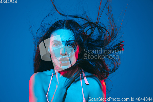 Image of Attractive brunette model on blue studio background in neon light