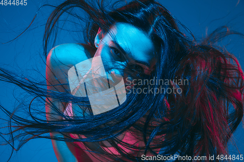 Image of Attractive brunette model on blue studio background in neon light