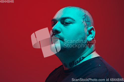 Image of Portrait of a guy with colorful neon light on red background - cyberpunk concept