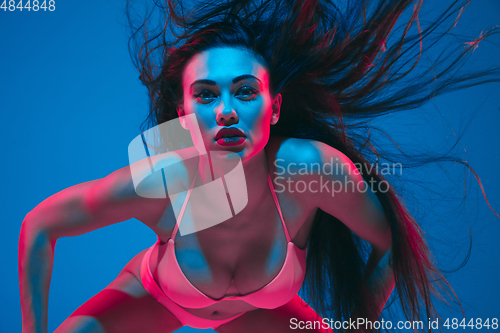 Image of Attractive brunette model on blue studio background in neon light