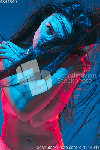 Image of Attractive brunette model on blue studio background in neon light