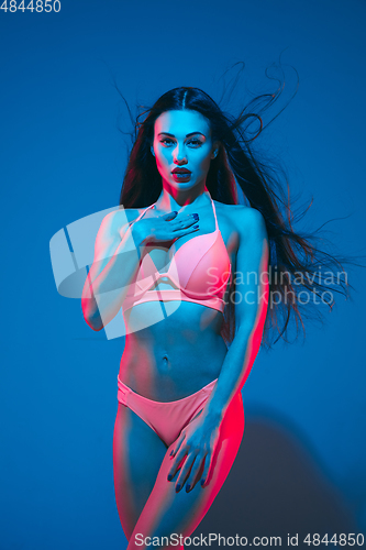 Image of Attractive brunette model on blue studio background in neon light