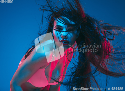 Image of Attractive brunette model on blue studio background in neon light