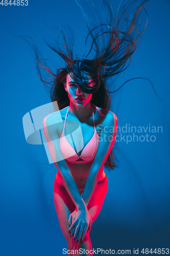 Image of Attractive brunette model on blue studio background in neon light