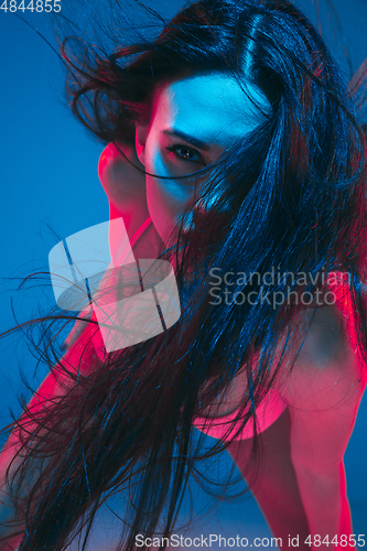 Image of Attractive brunette model on blue studio background in neon light