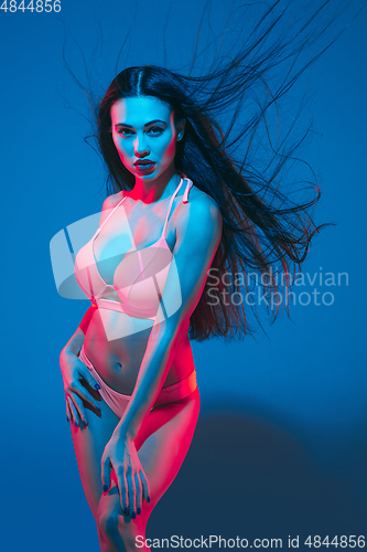 Image of Attractive brunette model on blue studio background in neon light