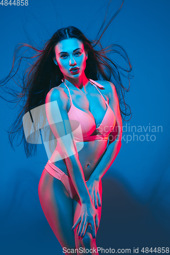 Image of Attractive brunette model on blue studio background in neon light