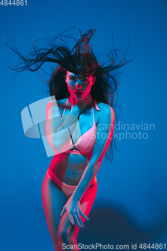Image of Attractive brunette model on blue studio background in neon light