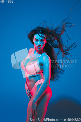 Image of Attractive brunette model on blue studio background in neon light