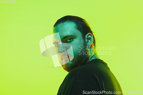 Image of Portrait of a guy with colorful neon light on green background - cyberpunk concept