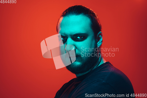 Image of Portrait of a guy with colorful neon light on red background - cyberpunk concept