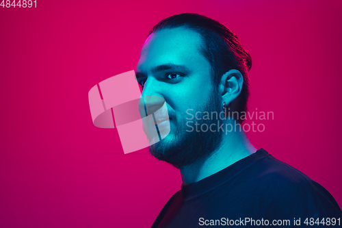 Image of Portrait of a guy with colorful neon light on pink background - cyberpunk concept