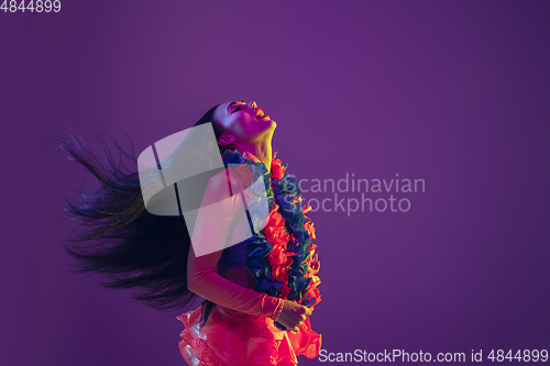 Image of Attractive hawaiian brunette model on purple studio background in neon light