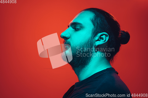 Image of Portrait of a guy with colorful neon light on red background - cyberpunk concept